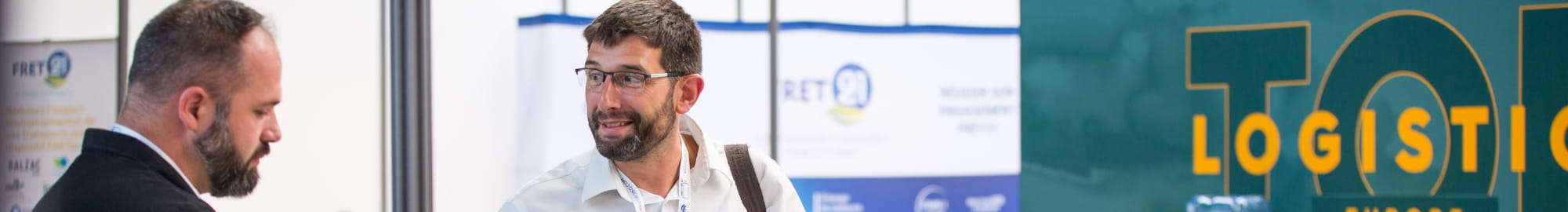 Personnes souriantes qui discutent devant une affiche de Top Logistics Europe