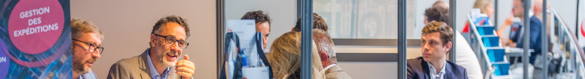 Personnes souriantes installées à différents stands pour discuter business dans le secteur logistique