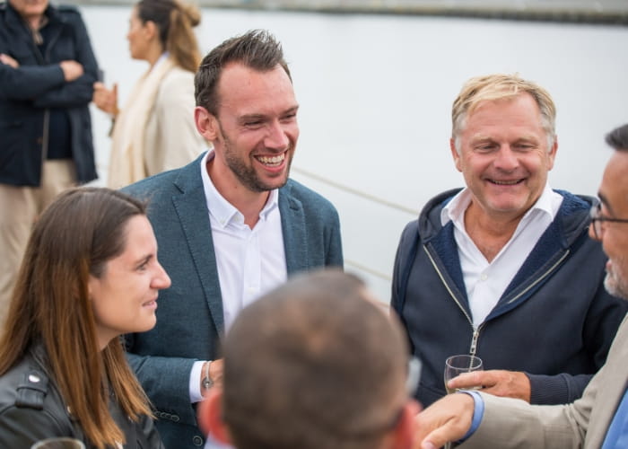 A group of people laughing and chatting on a boat during a top logistics europe evening.