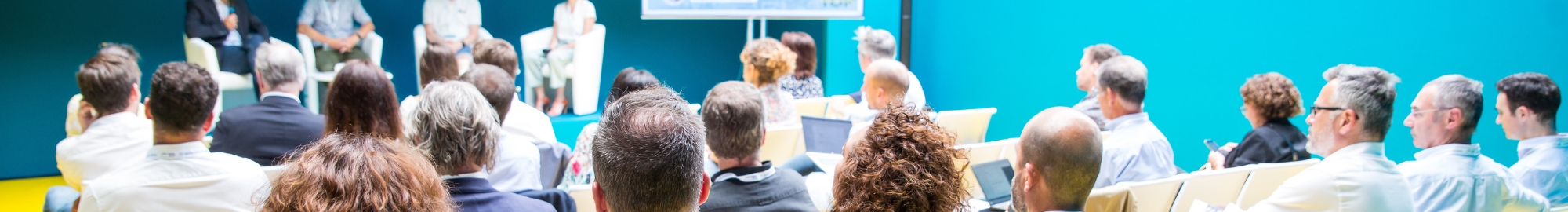 Salle de conférence remplie de personnes attentives qui écoutent les intervenants