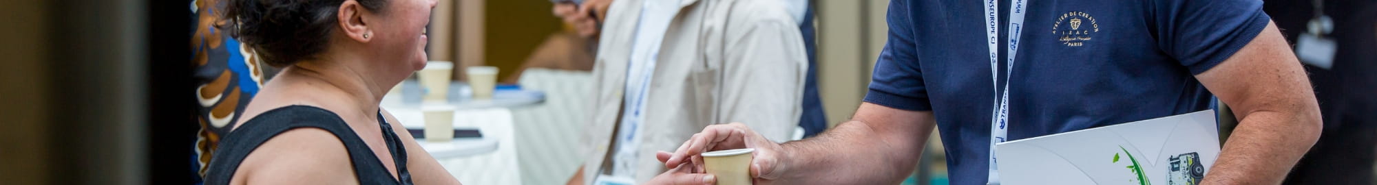 Personnes souriantes qui échangent, se donnent un café à la pause café parmi les stands de top logistics europe