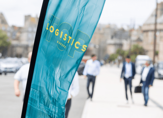 Bannière flottante de top logistics europe, avec des personnes en costards qui marchent vers le Quai Saint-Malo.