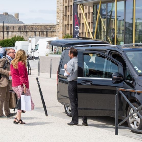 Groupe de personnes discutant avec chauffeur de van à côté de son véhicule devant le Palais du Grand Large.