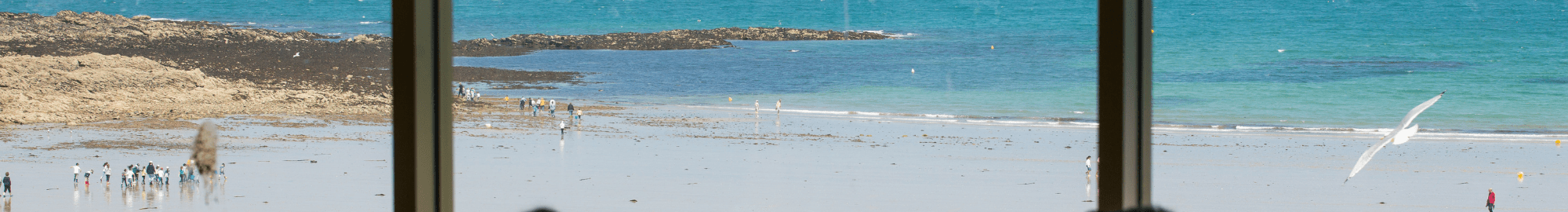 Un homme qui photographie la plage ensoleillée de Saint-malo depuis la salle de déjeuner, la Rotonde du Palais du Grand Large