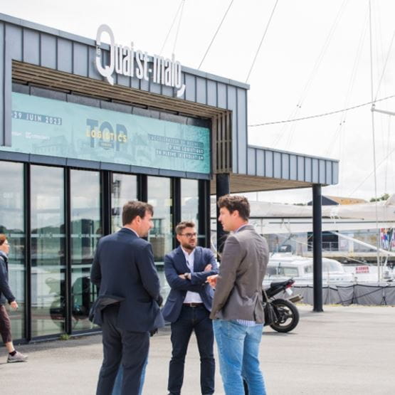 Groupe de personnes discutant devant le Quai Saint-Malo sur le port, devant une bannière Top Logistics Europe